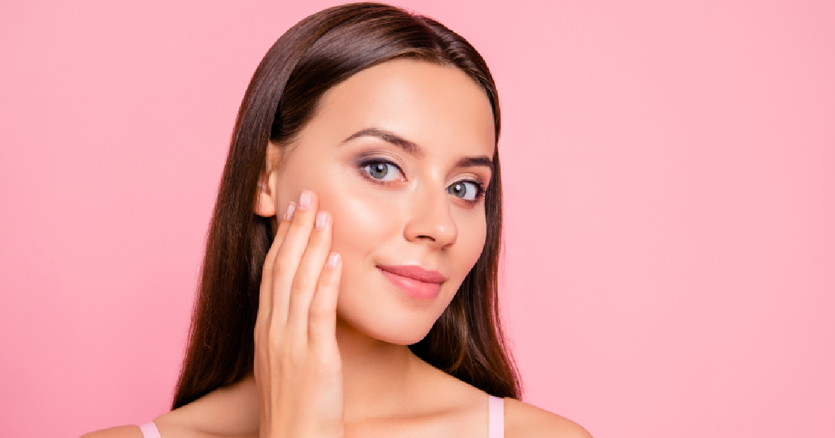 Woman with smooth glowing skin touching her face after Dermaplaning in Cary, NC.